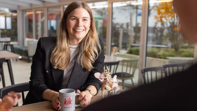 Uma colaboradora da KiK assegura a organização dos artigos têxteis nas prateleiras da loja.