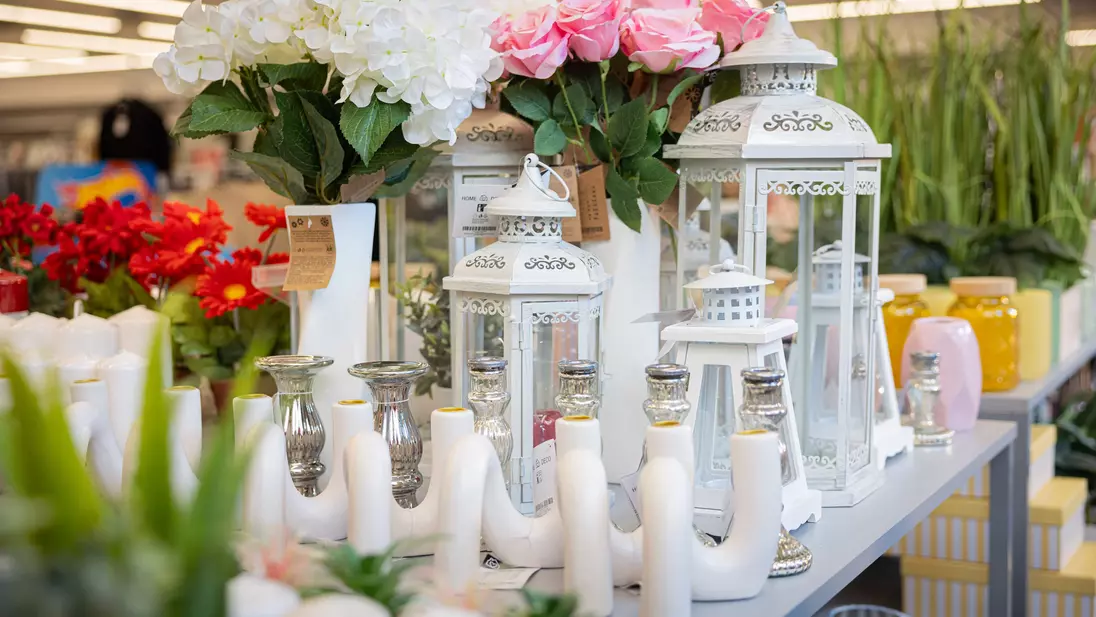 Artigos de decoração e flores artificiais, que fazem parte da gama de produtos não alimentares da KiK, apresentados numa mesa com degraus na zona de entrada