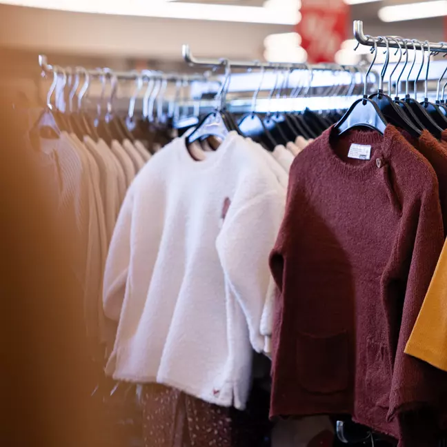 Parte do sortido de têxteis para criança exposto num suporte de roupa numa loja KiK