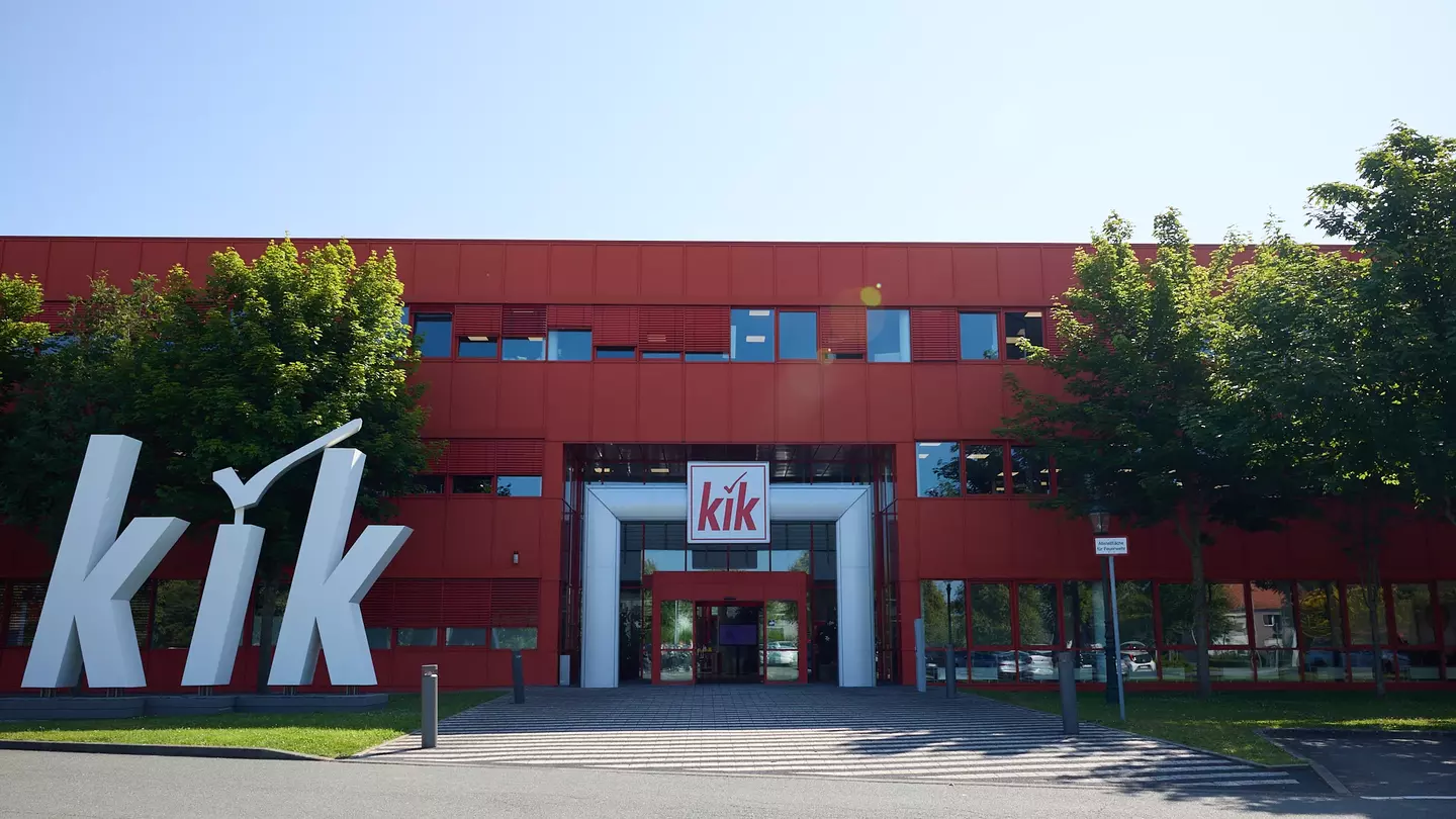 Entrada principal da sede da KiK em Bönen, com um grande logótipo da KiK em destaque.