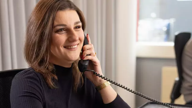 Uma colaboradora está sentada à sua secretária a falar ao telefone