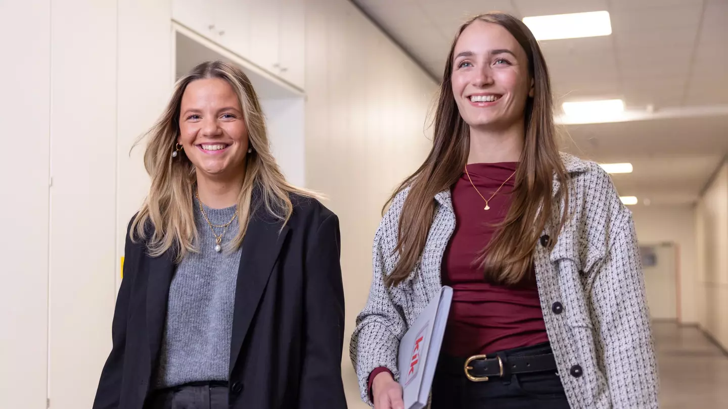 Na sede da KiK, duas colaboradoras seguem pelo corredor com um sorriso no rosto