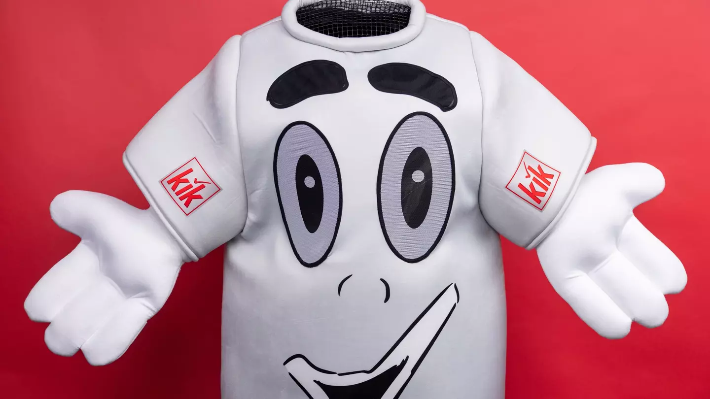 A mascote da KiK, com os braços abertos, sorri amigavelmente para a câmara
