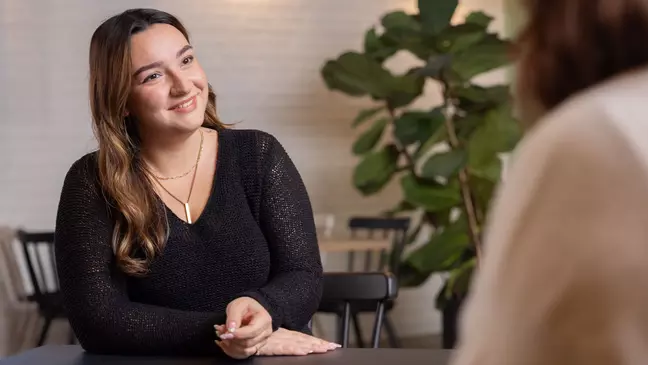 Eine Frau sitzt in einer modernen Lounge und lächelt