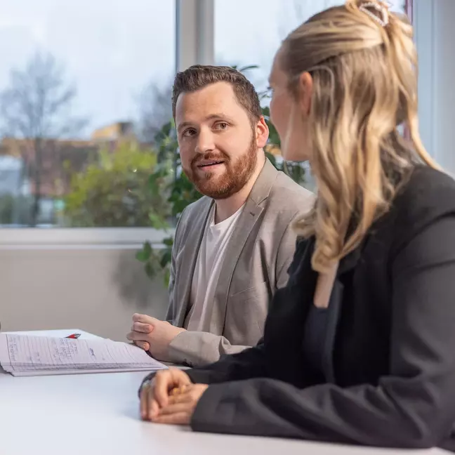 Duas pessoas participam numa entrevista de emprego num escritório moderno.